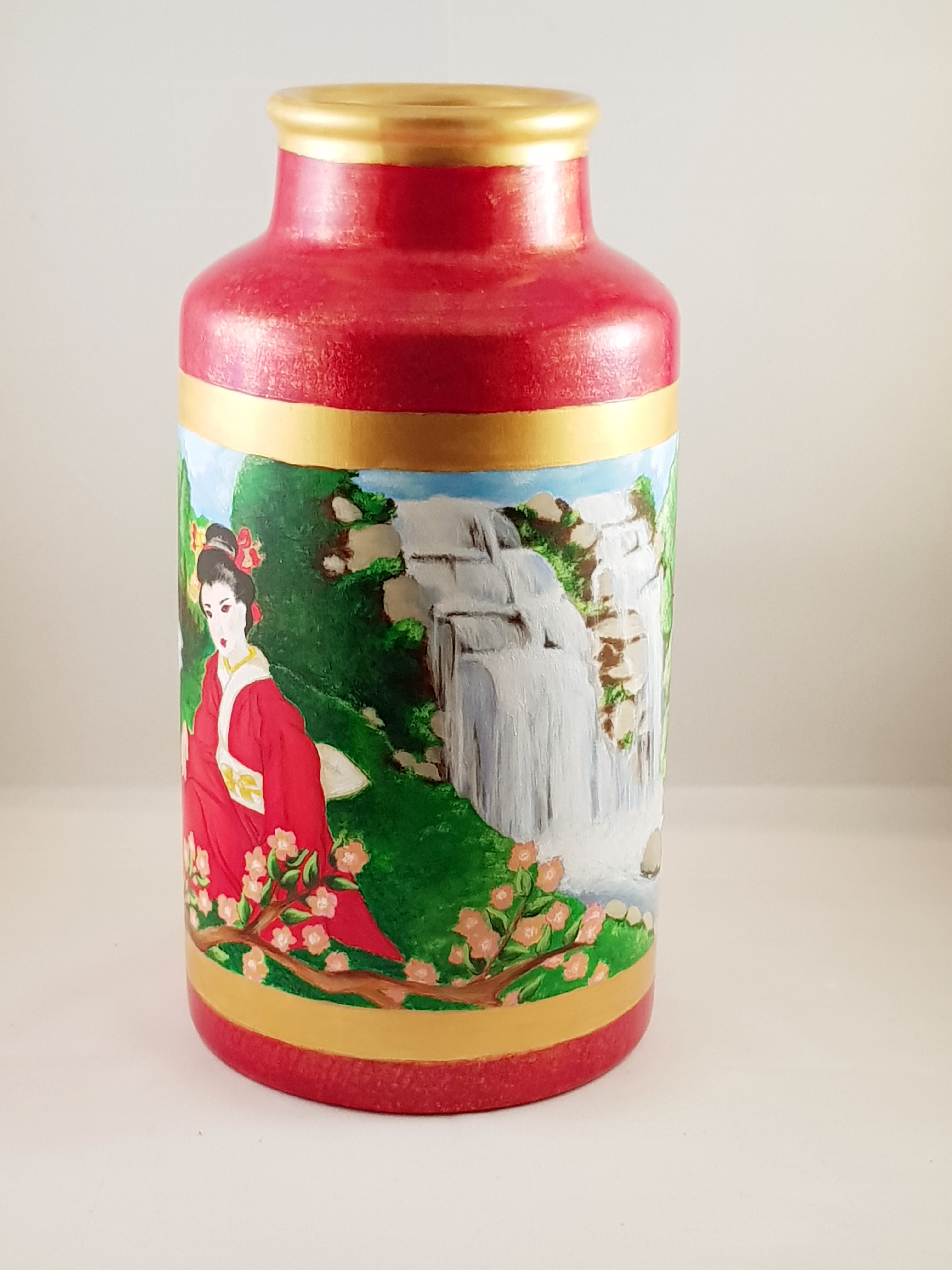 Painted geisha near waterfall on ceramic vase.